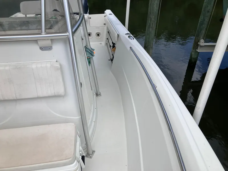 Slide: The Image of 2005 Sailfish 266 CC boat deck, white seating, docked by water. - 29