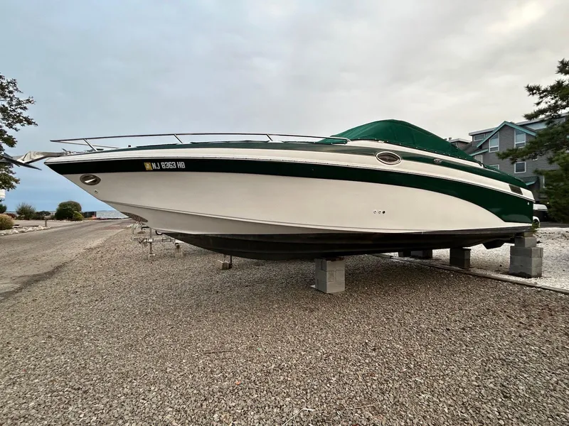 Slide: The Image of 2001 Crownline 288 BR boat on gravel, green and white exterior, elevated on blocks. - 3