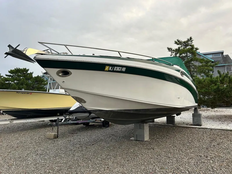 Slide: The Image of 2001 Crownline 288 BR boat on dry dock, green and white exterior, parked on gravel. - 4