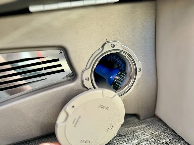 Slide: The Image of 2022 Tahoe Pontoon Cascade Platinum storage compartment with blue hose. - 31