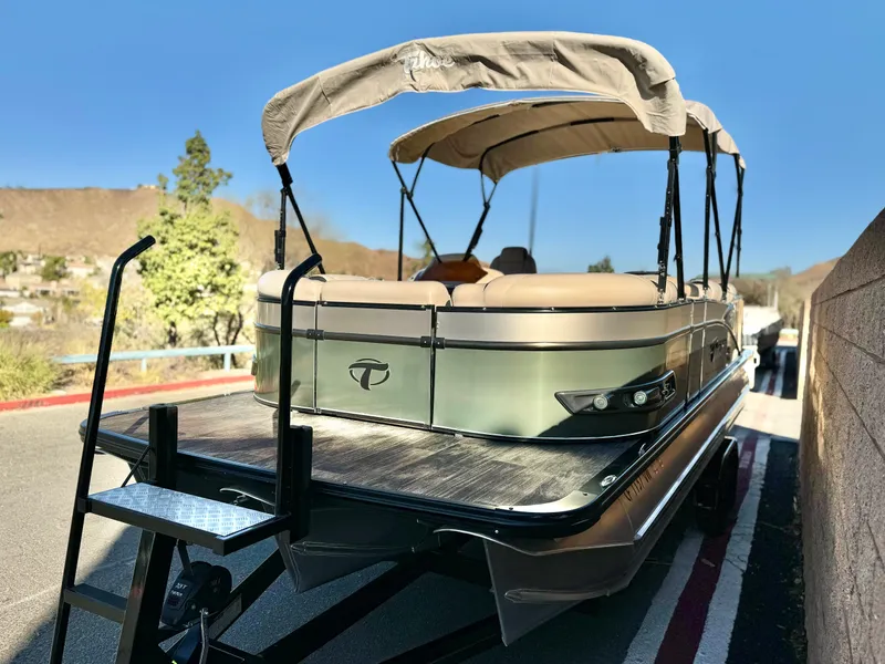 Slide: The Image of 2022 Tahoe Pontoon Cascade Platinum Rear J Lounger on trailer, outdoor setting. - 4