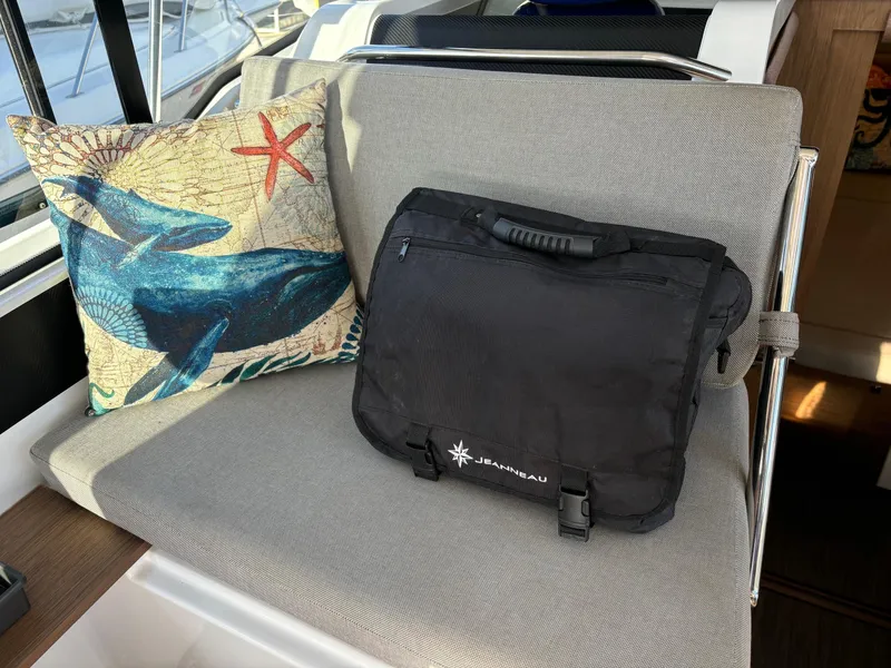 Slide: The Image of Cushioned seating on 2018 Jeanneau NC 895 with decorative pillow and black bag. - 14
