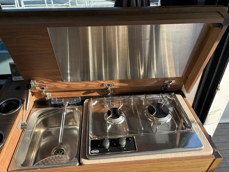 Slide: The Image of 2018 Jeanneau NC 895 boat kitchen with sink and dual-burner stove. - 25