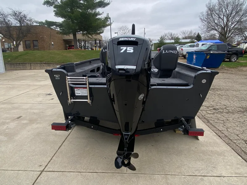 Slide: The Image of 2025 Lund 1775 Pro Guide boat with Mercury 75 engine, parked outdoors. - 2