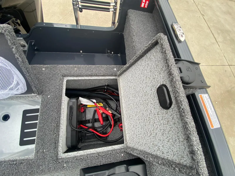 Slide: The Image of 2025 Lund 1775 Pro Guide boat battery compartment with open hatch and visible wiring. - 23