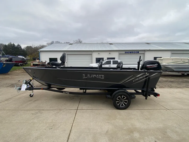 Slide: The Image of 2025 Lund 1775 Pro Guide boat on trailer, parked outside a showroom. - 4