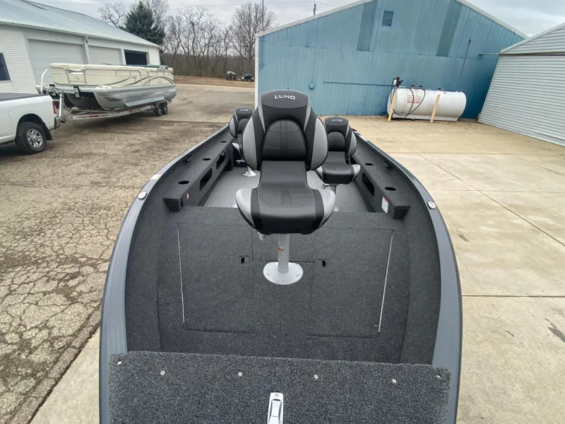 Slide: The Image of 2025 Lund 1775 Pro Guide boat with seating, parked outdoors near blue building. - 8