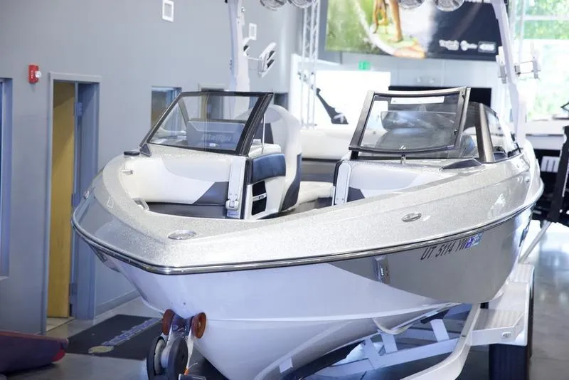 Slide: The Image of 2016 Malibu 23 LSV boat displayed indoors, sleek design, white exterior. - 17