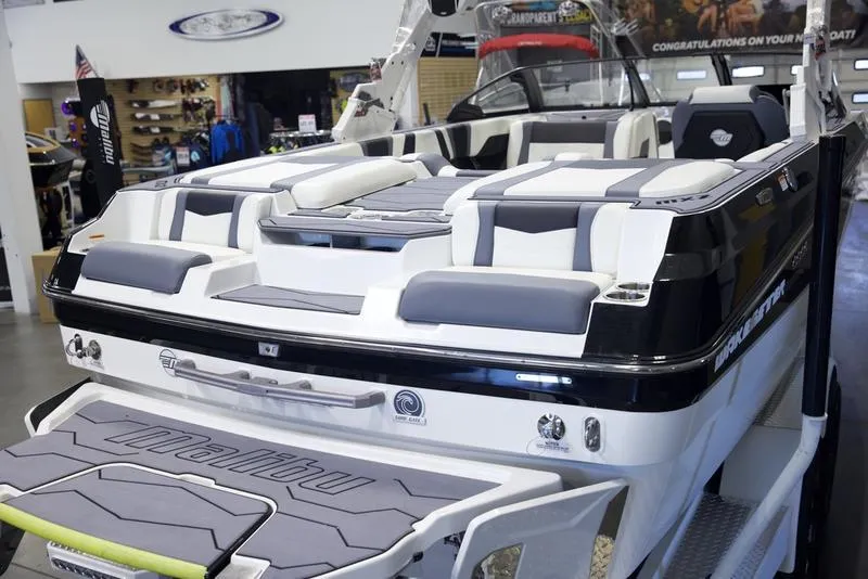 Slide: The Image of 2025 Malibu 22 MXZ boat interior, featuring sleek seating and modern design in showroom. - 18