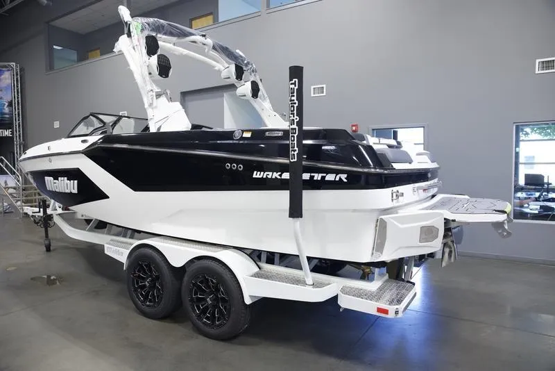 Slide: The Image of 2025 Malibu 22 MXZ boat in showroom, black and white design, on a trailer. - 3