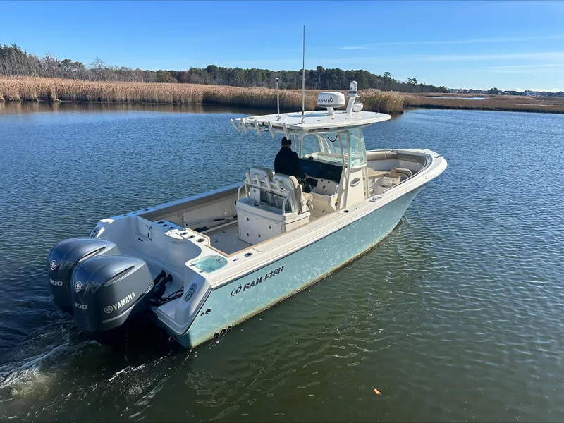 Slide: The Image of 2020 Sailfish 290 CC boat with twin Yamaha engines on a calm waterway. - 1