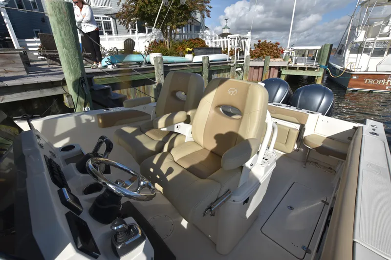 Slide: The Image of 2020 Sailfish 290 CC boat interior with beige seats and dual engines at dock. - 20