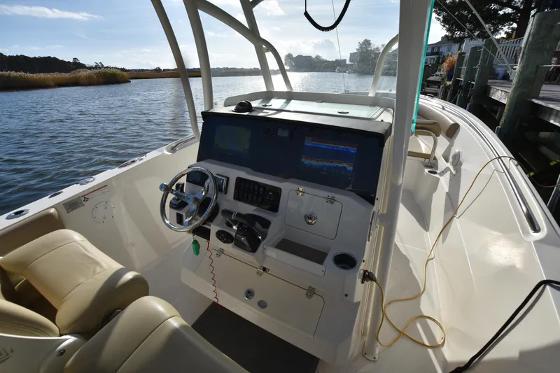Slide: The Image of 2020 Sailfish 290 CC boat interior with steering console and seating, docked by a serene waterway. - 27