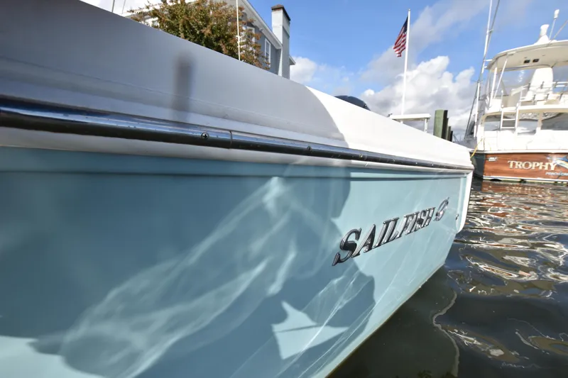 Slide: The Image of 2020 Sailfish 290 CC boat docked, reflecting sunlight on water. - 37