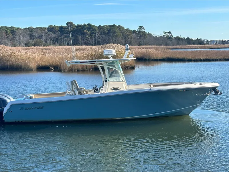 Slide: The Image of 2020 Sailfish 290 CC boat on calm water, surrounded by reeds and trees. - 4