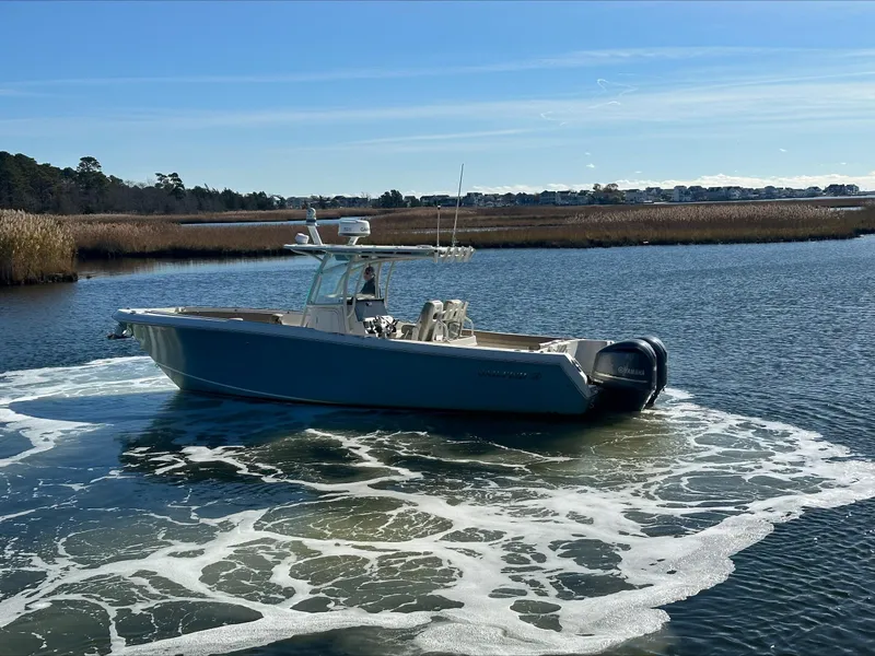 Slide: The Image of 2020 Sailfish 290 CC boat cruising on a calm lake with scenic background. - 46