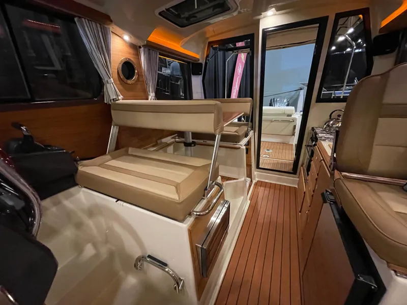Slide: The Image of Interior of 2025 Ranger Tugs R-27 boat with modern seating and wood flooring. - 9