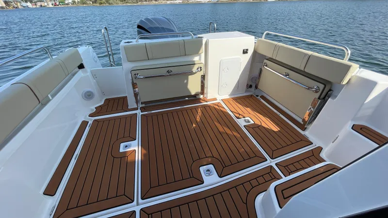 Slide: The Image of 2025 Ranger Tugs R-25 boat deck with wood finish, spacious seating, and scenic water view. - 13