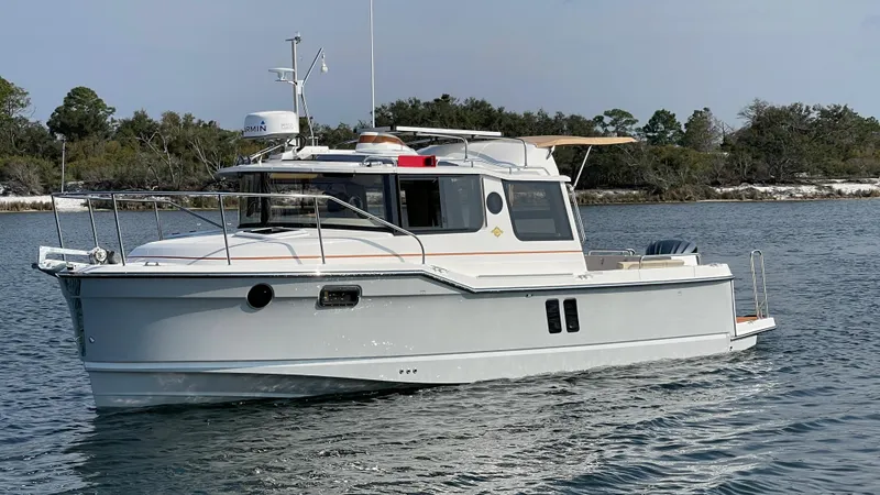 Slide: The Image of 2025 Ranger Tugs R-25 boat on calm water, surrounded by trees. - 19