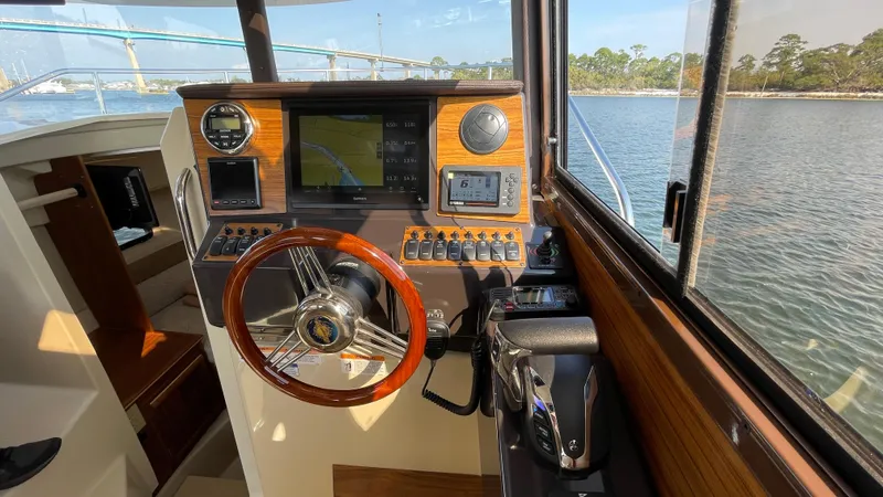 Slide: The Image of 2025 Ranger Tugs R-25 helm with wooden steering wheel and navigation controls. - 49