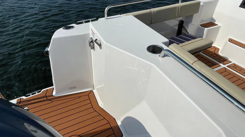 Slide: The Image of 2025 Ranger Tugs R-25 boat deck with teak flooring and seating, on calm water. - 9