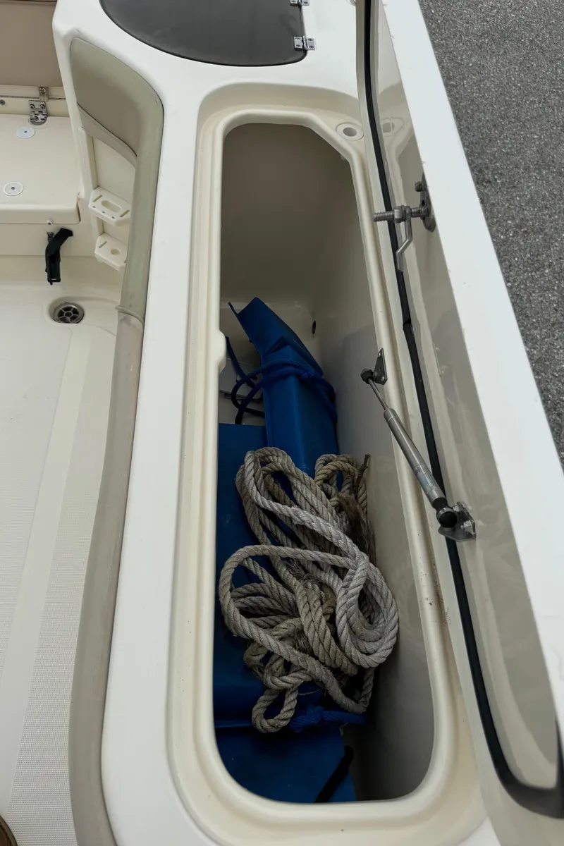 Slide: The Image of Open storage compartment on 2011 Scout 282 XSF boat with rope and blue equipment. - 12
