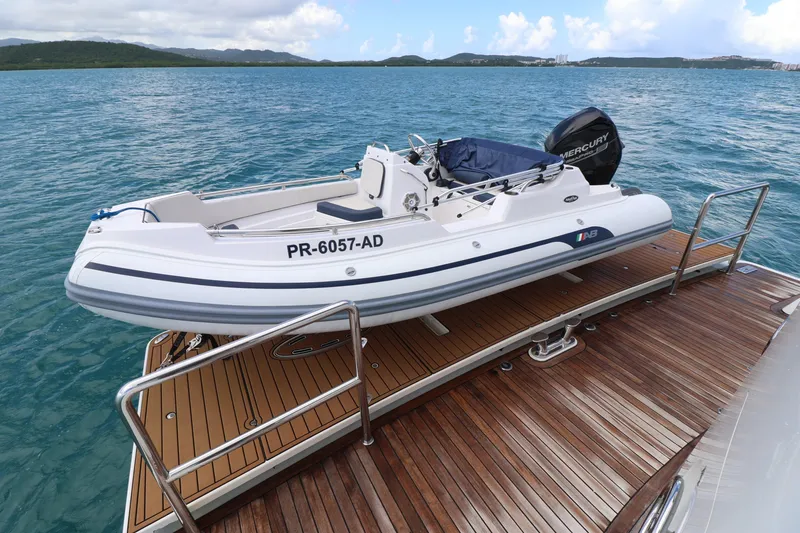 Slide: The Image of 2013 Cheoy Lee Bravo yacht with a small boat on deck, docked on calm waters. - 16