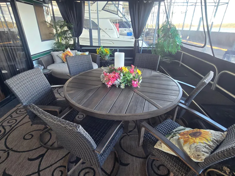 Slide: The Image of Luxurious Sumerset 82'x18' houseboat interior with elegant dining area, wicker chairs, and floral centerpiece. - 5