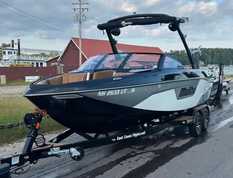Slide: The Image of 2022 Malibu Wakesetter 23 LSV boat on trailer, parked near red building. - 4