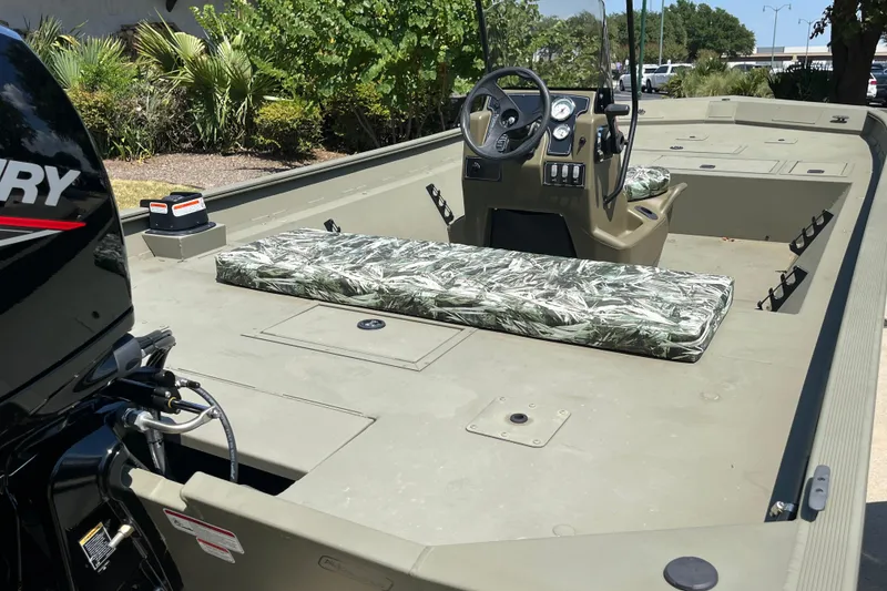 Slide: The Image of 2025 Tracker Grizzly 2072 CC boat with camo seating and Mercury engine, outdoors. - 3