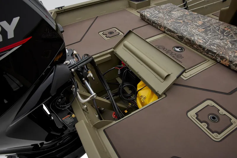 Slide: The Image of 2025 Tracker Grizzly 2072 CC boat interior with open storage compartment and camouflage seat. - 21