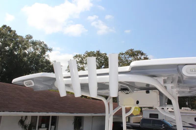 Slide: The Image of 2025 NauticStar 224 Bay boat with rod holders and canopy, outdoors. - 17