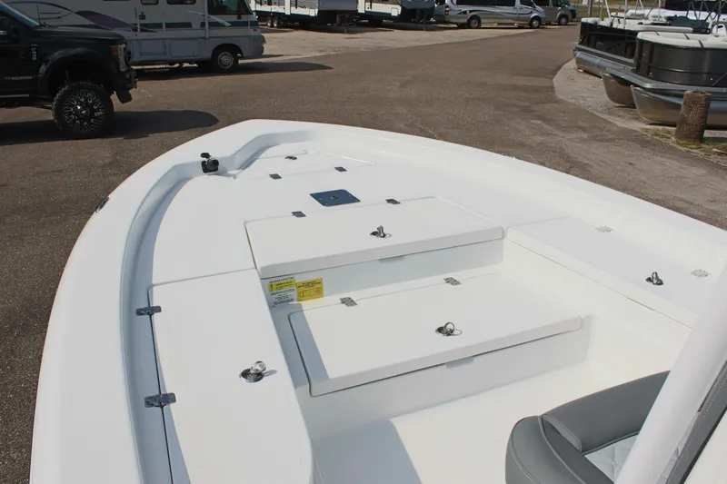 Slide: The Image of 2025 NauticStar 224 Bay boat interior with storage compartments, parked in a marina. - 22
