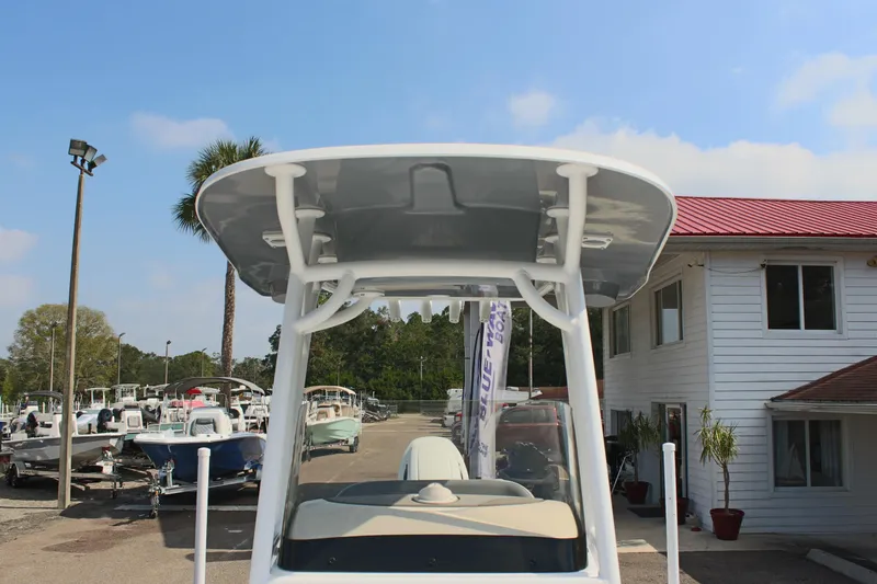 Slide: The Image of 2025 NauticStar 224 Bay boat at a marina with palm trees and blue sky. - 30