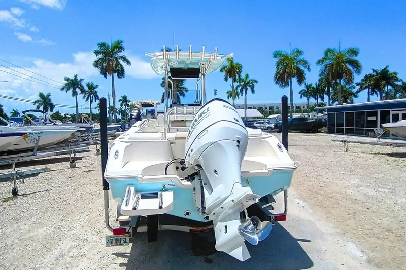 Slide: The Image of 2025 Bulls Bay 230 Center Console boat with outboard motor, parked under palm trees. - 5