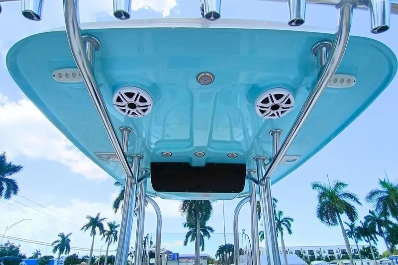 Slide: The Image of 2025 Bulls Bay 230 Center Console boat with blue T-top and speakers, palm trees in background. - 13