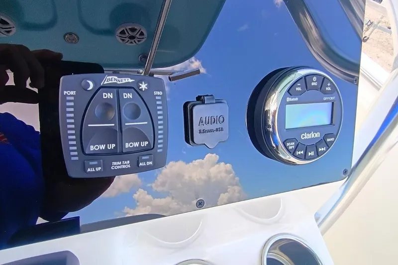 Slide: The Image of 2025 Bulls Bay 230 Center Console dashboard with trim tab controls and Clarion audio system. - 20