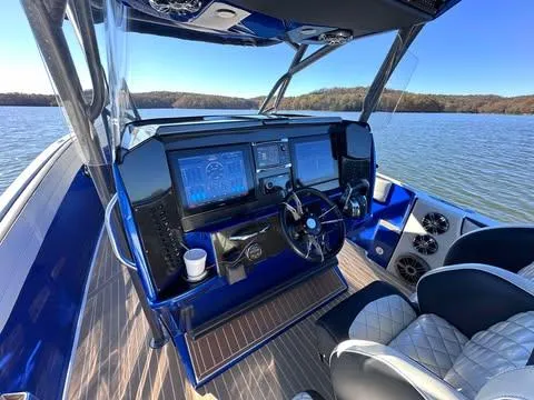 Slide: The Image of 2015 Nor-Tech 340 Sport Center Console boat dashboard with dual screens on a lake. - 11