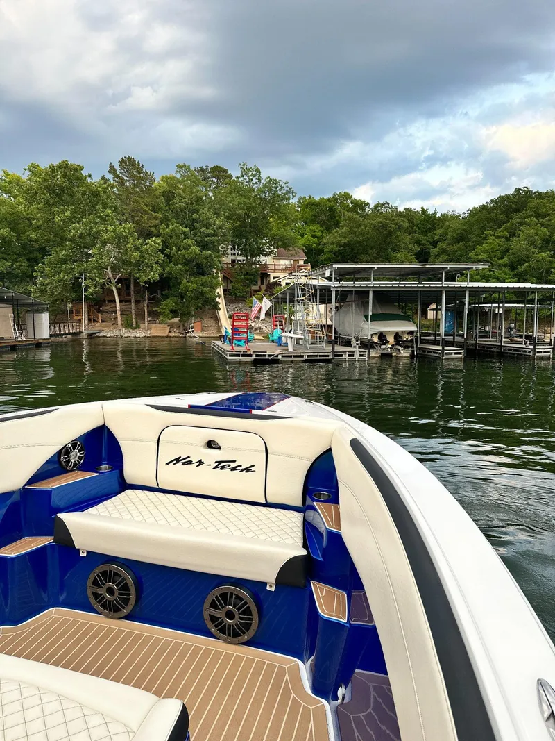 Slide: The Image of 2015 Nor-Tech 340 Sport Center Console boat on a scenic lake with docks and trees. - 15