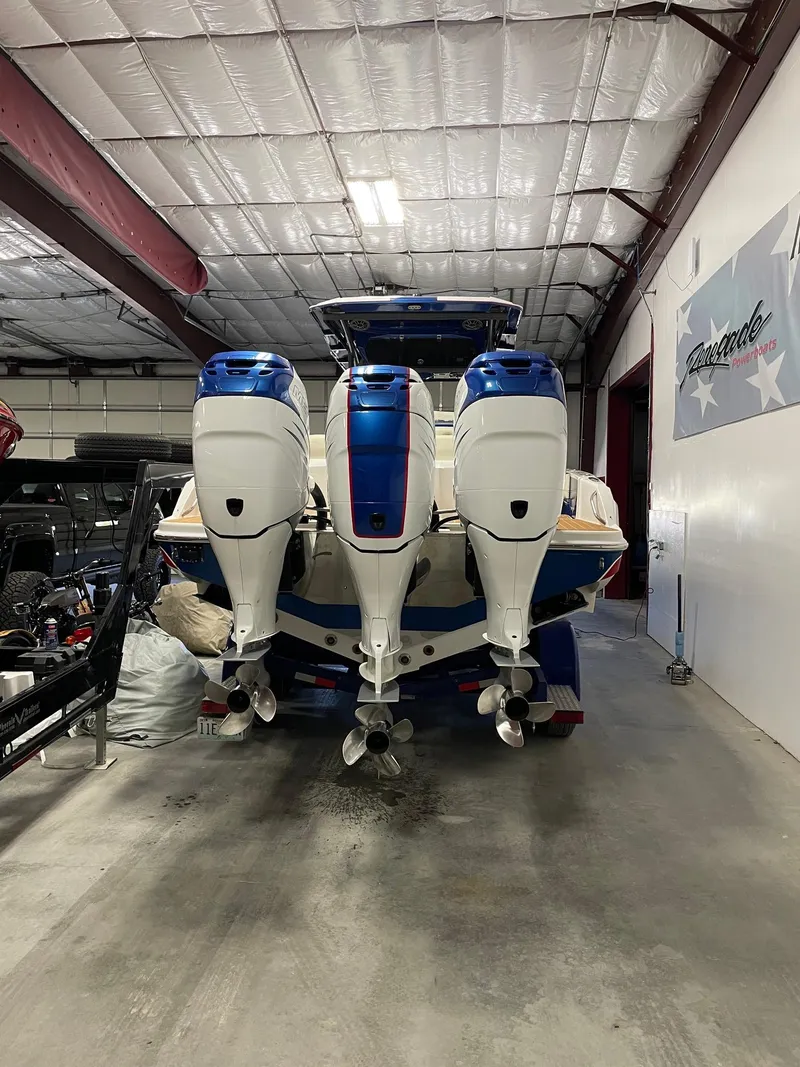 Slide: The Image of 2015 Nor-Tech 340 Sport Center Console with triple outboard engines in a storage facility. - 17