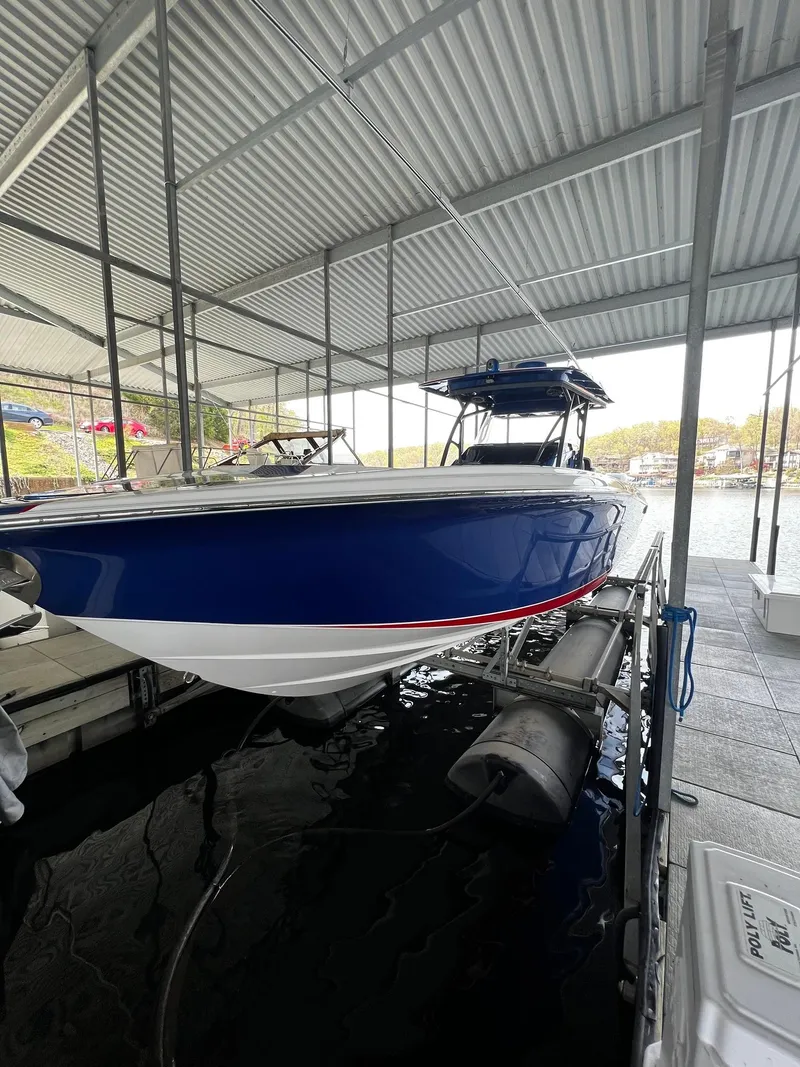Slide: The Image of 2015 Nor-Tech 340 Sport Center Console boat in dock, blue hull, covered marina. - 23