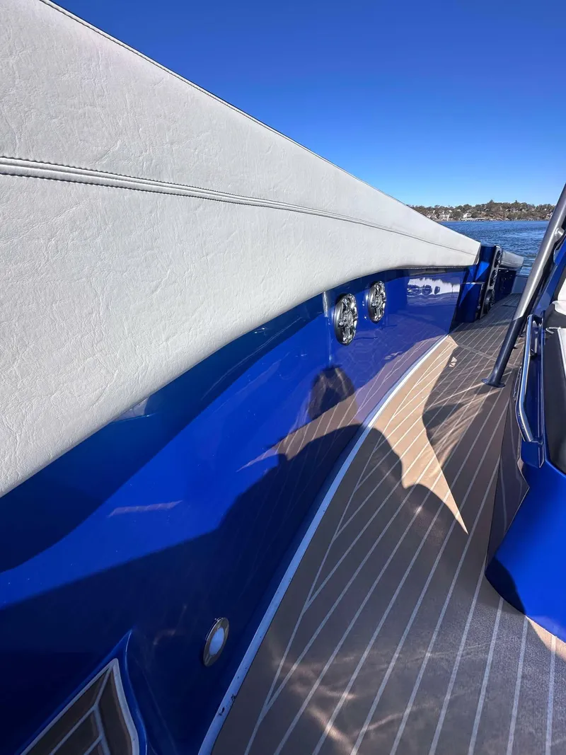 Slide: The Image of 2015 Nor-Tech 340 Sport Center Console, sleek blue exterior, wooden deck, clear sky background. - 24