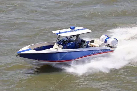 Slide: The Image of 2015 Nor-Tech 340 Sport Center Console boat speeding on water, blue and white design. - 4