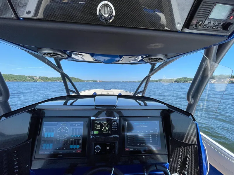 Slide: The Image of 2015 Nor-Tech 340 Sport Center Console dashboard with dual screens, on a scenic waterway. - 9
