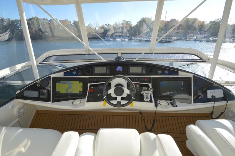 Slide: The Image of 2007 Marquis 59 yacht helm with navigation screens and steering wheel on a sunny day. - 2