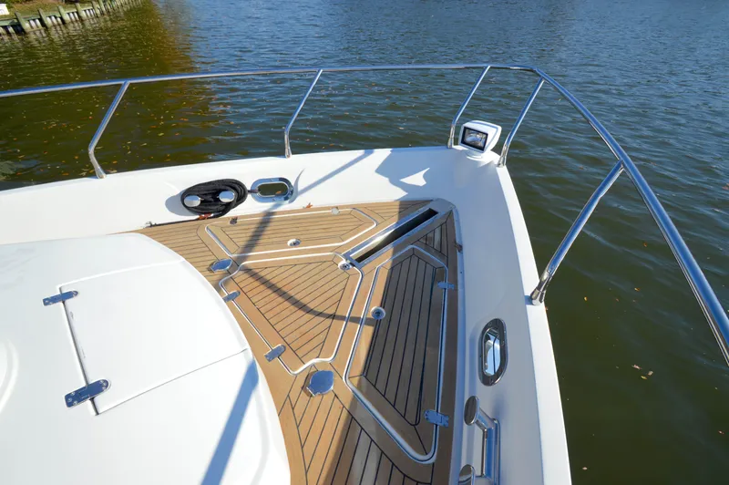 Slide: The Image of 2007 Marquis 59 yacht deck with teak flooring and stainless steel railings on calm water. - 27