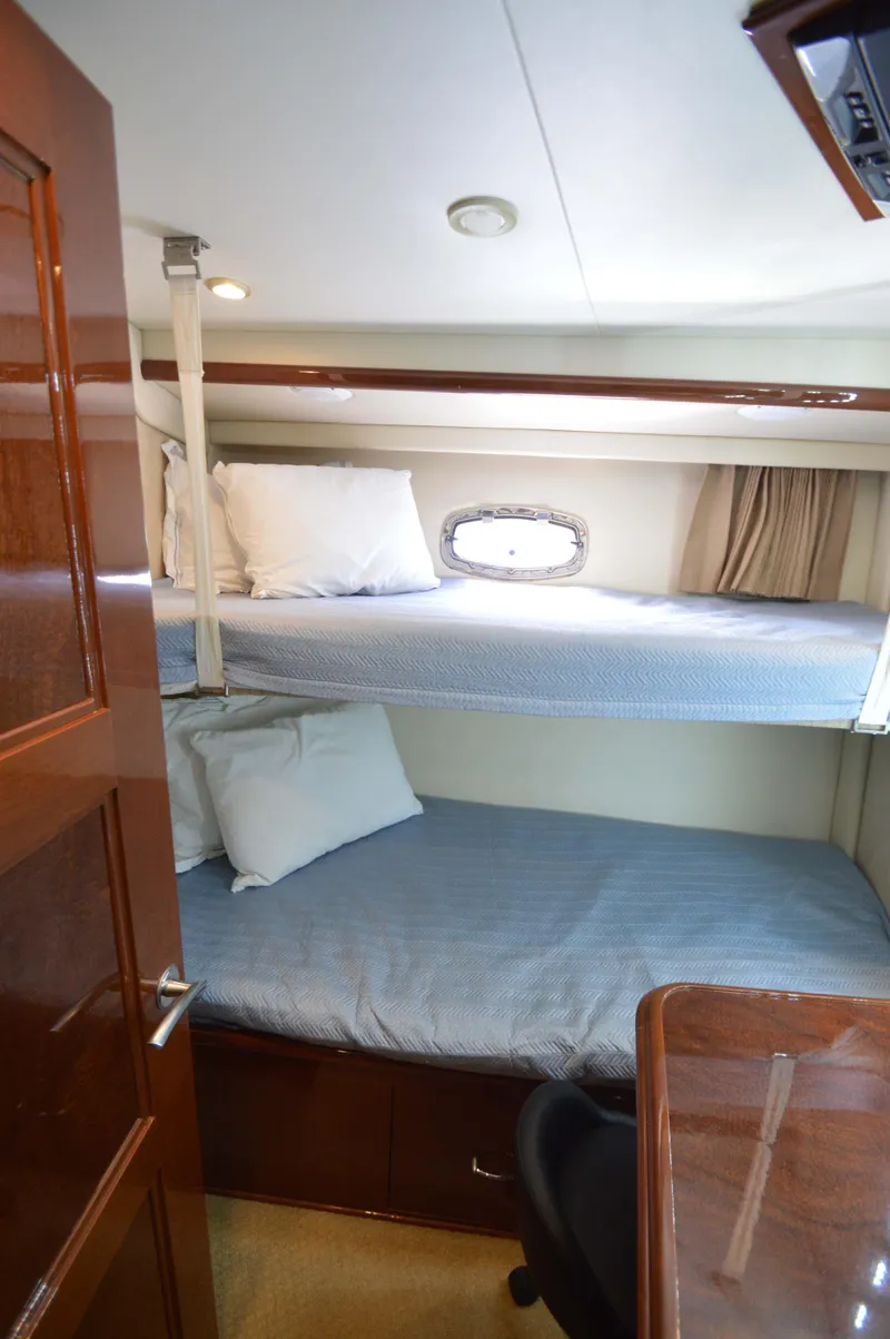 Slide: The Image of Bunk beds in 2007 Marquis 59 yacht cabin with wooden finishes and porthole window. - 49