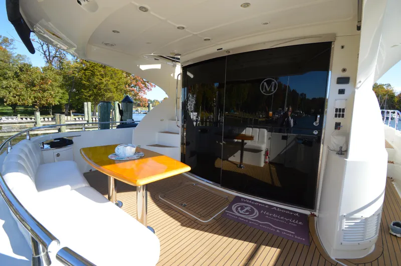 Slide: The Image of Luxurious 2007 Marquis 59 yacht deck with seating and table, docked in a scenic marina. - 9