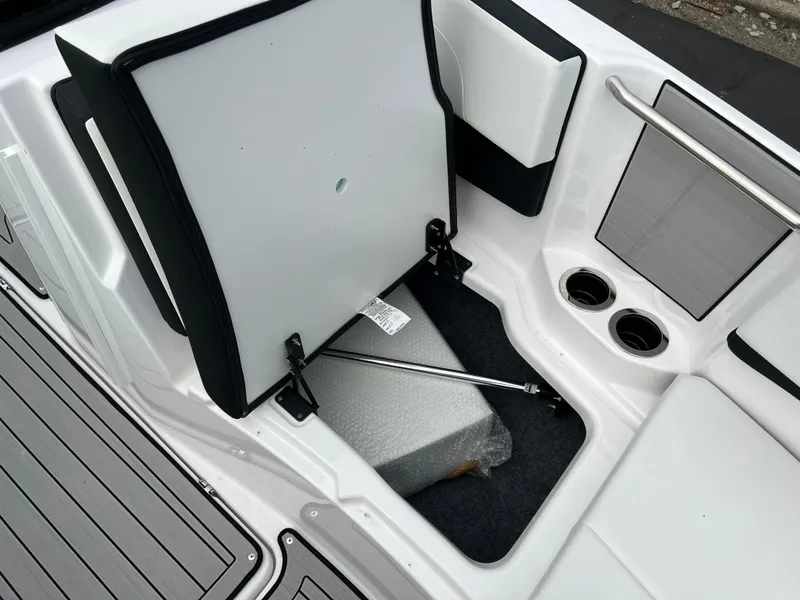 Slide: The Image of 2025 Yamaha Boats 222SE storage compartment with open seat and cup holders. - 16