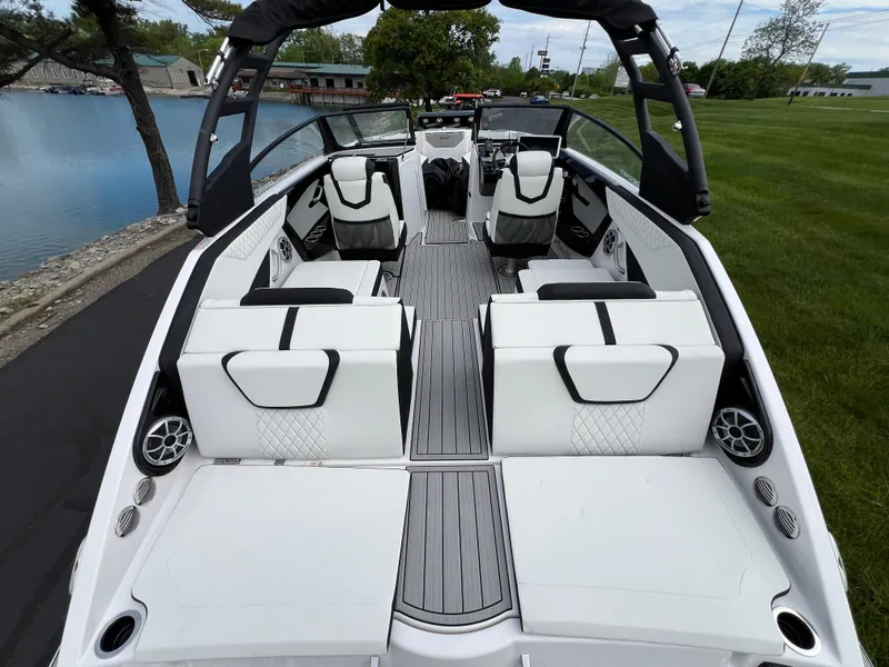 Slide: The Image of 2025 Yamaha Boats 222SE interior, featuring sleek white seating and modern design by a lakeside. - 8